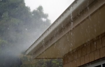 Rainwater spills over a traditional gutter on a house.